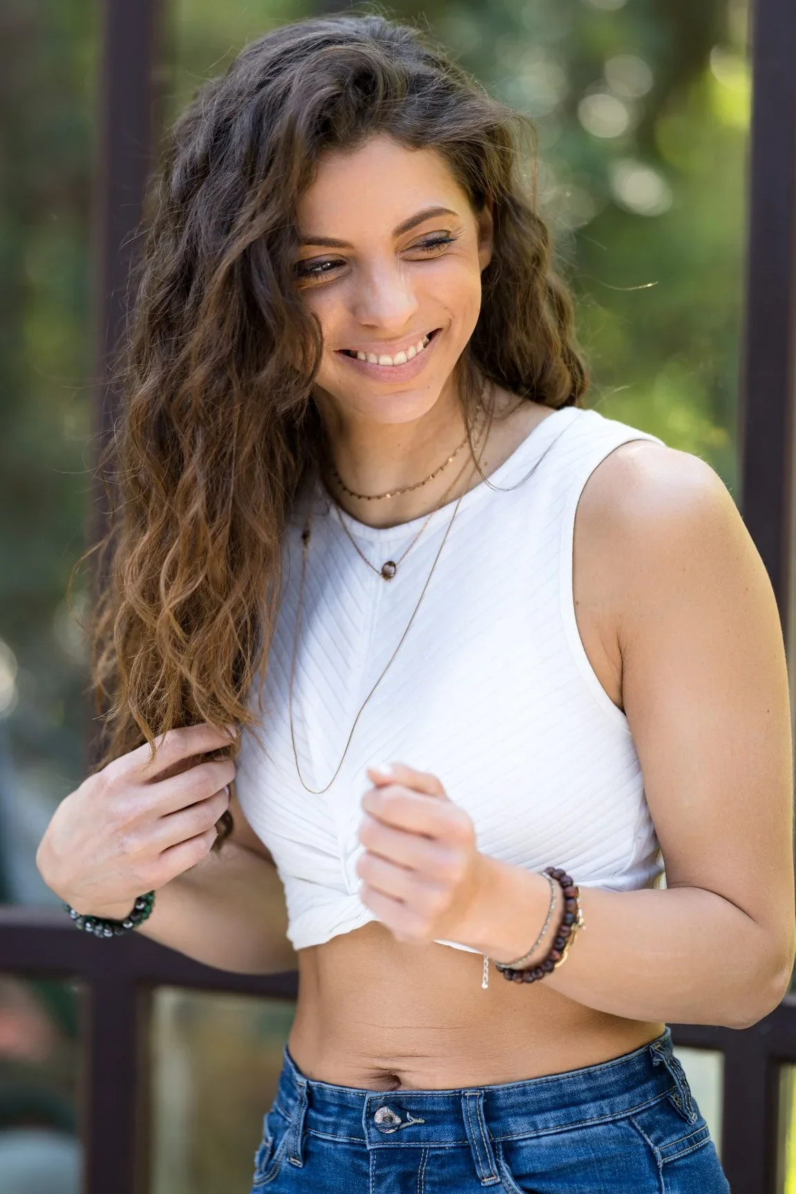 Portrait en lumière naturelle d’une femme souriante en haut blanc