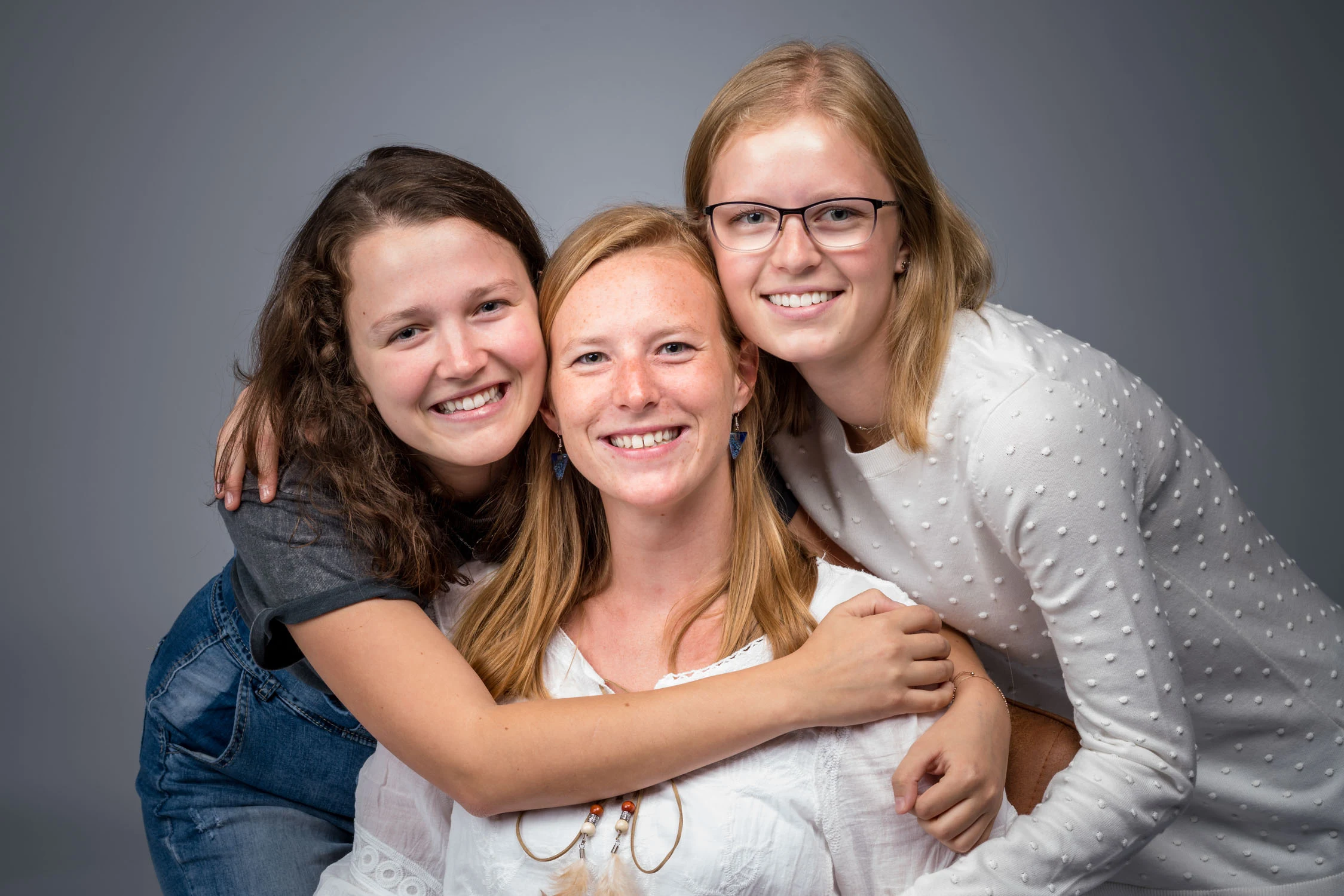 Trois femmes souriantes enlacées au studio